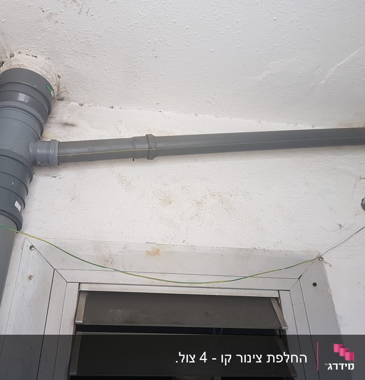 צינור פלסטיק אפור מותקן על קיר לבן